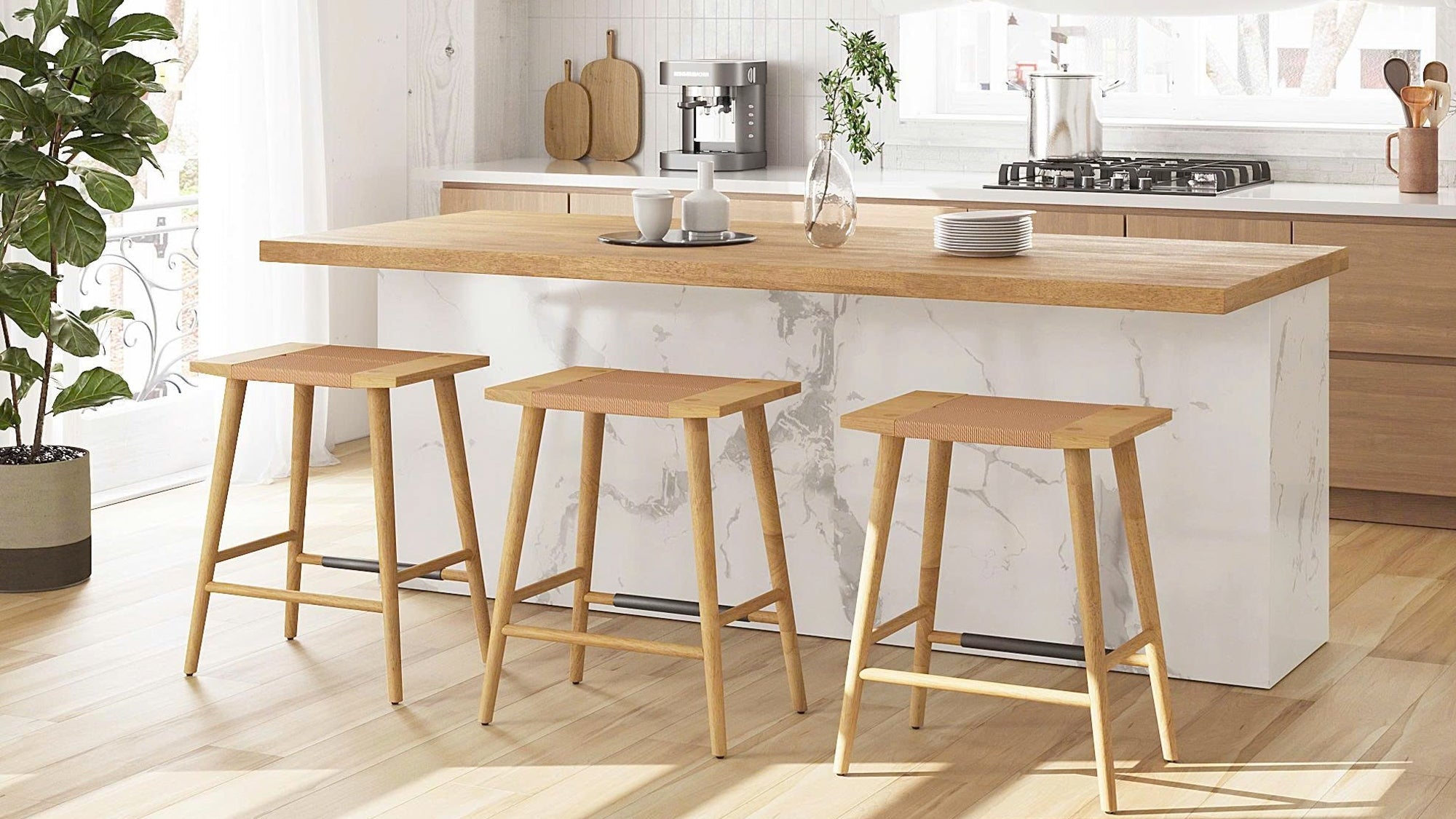 Modern kitchen with wooden island and stools, featuring a coffee machine and kitchenware.